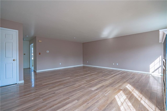 unfurnished room featuring baseboards and light wood finished floors