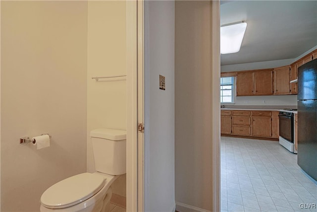 bathroom with tile patterned flooring, toilet, and baseboards