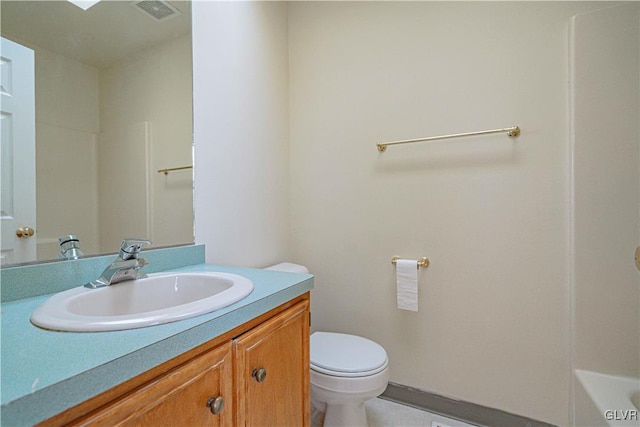 bathroom with vanity, toilet, visible vents, and a washtub