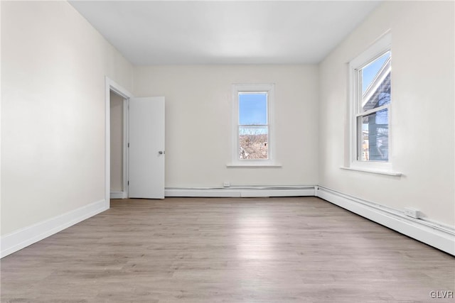 spare room with a healthy amount of sunlight, baseboards, and wood finished floors