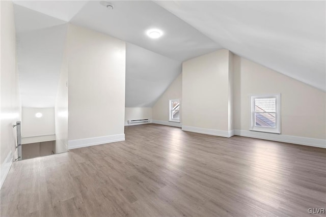 bonus room with baseboard heating, plenty of natural light, lofted ceiling, and wood finished floors