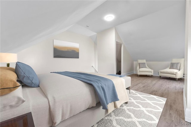 bedroom featuring vaulted ceiling, baseboards, and wood finished floors