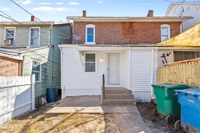 view of front of property featuring fence, brick siding, and a chimney