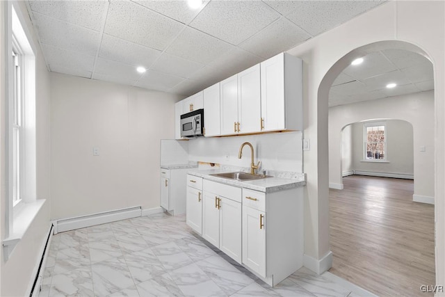 kitchen featuring stainless steel microwave, arched walkways, a baseboard radiator, and a sink