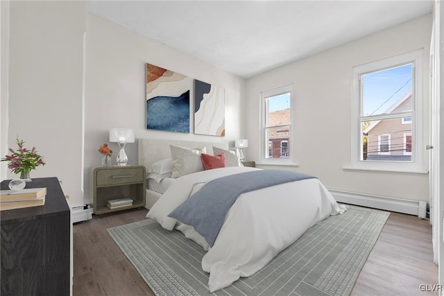 bedroom featuring wood finished floors, a baseboard heating unit, and a baseboard radiator