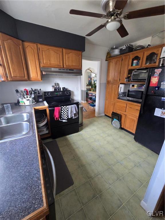 kitchen featuring black appliances, under cabinet range hood, a sink, arched walkways, and ceiling fan