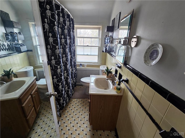 bathroom with vanity, tile walls, toilet, and a wainscoted wall