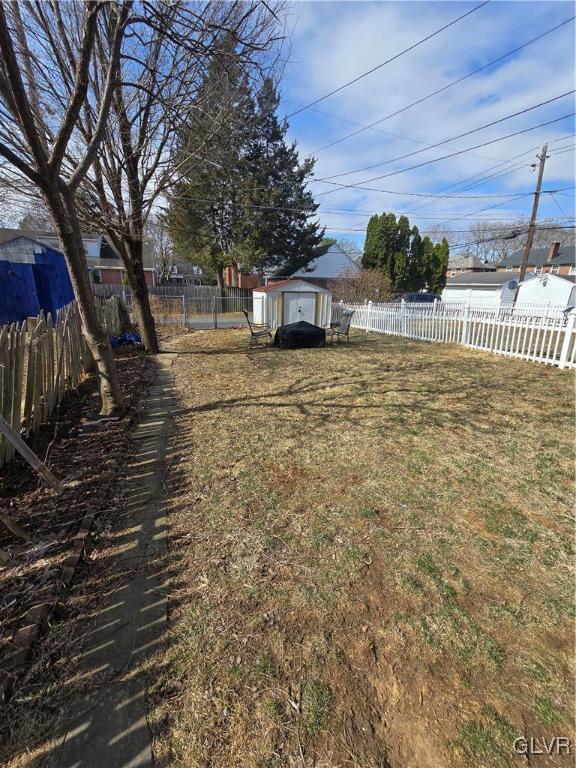 view of yard featuring a storage unit, an outdoor structure, and a fenced backyard