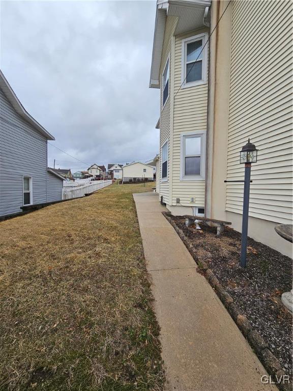 view of property exterior featuring a lawn and fence