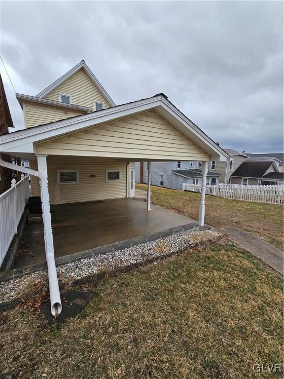 view of home's exterior featuring a lawn, an attached carport, and fence