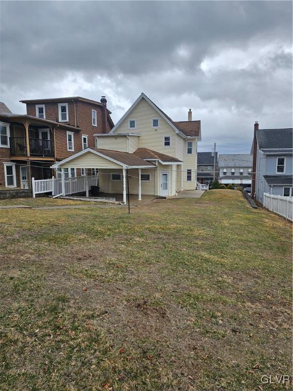 rear view of house with a yard, a patio, and fence