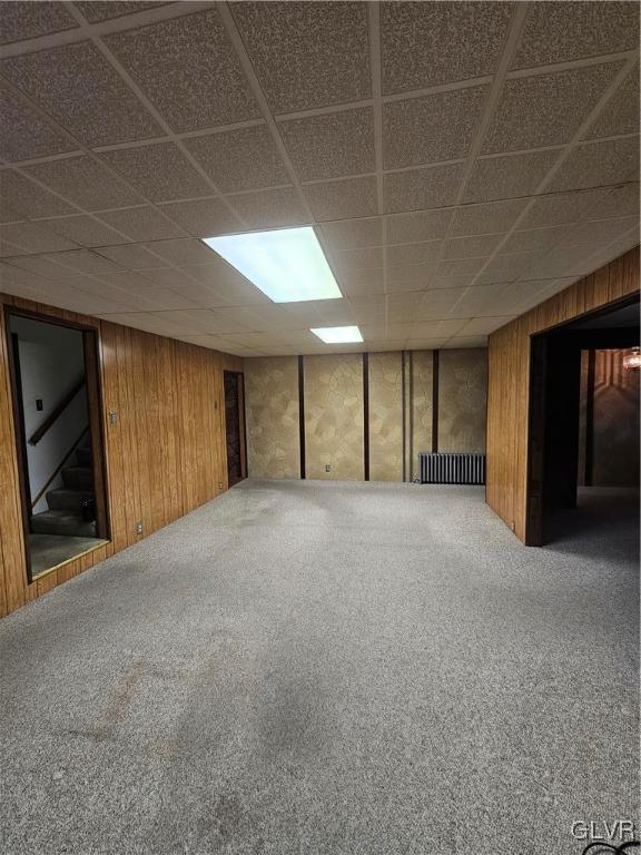 finished basement with stairway, wood walls, and carpet floors