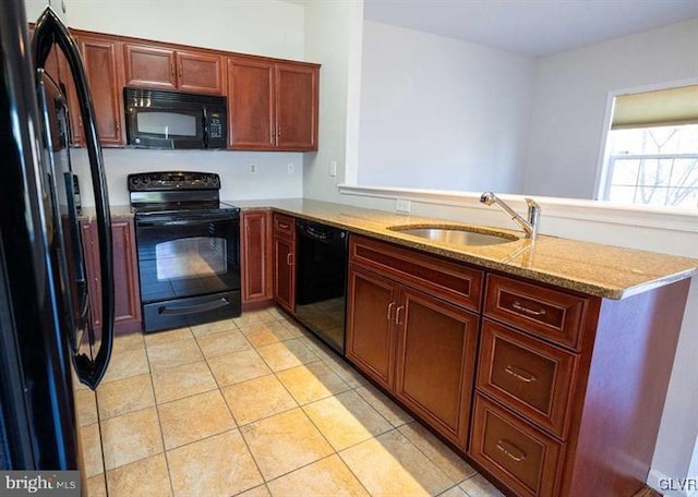 kitchen with light stone countertops, light tile patterned floors, a peninsula, black appliances, and a sink