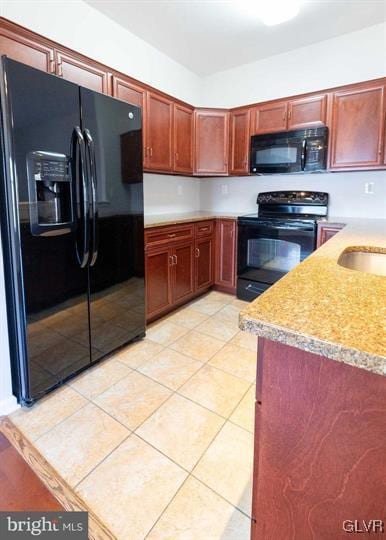 kitchen with light tile patterned flooring, a sink, black appliances, light countertops, and dark brown cabinets