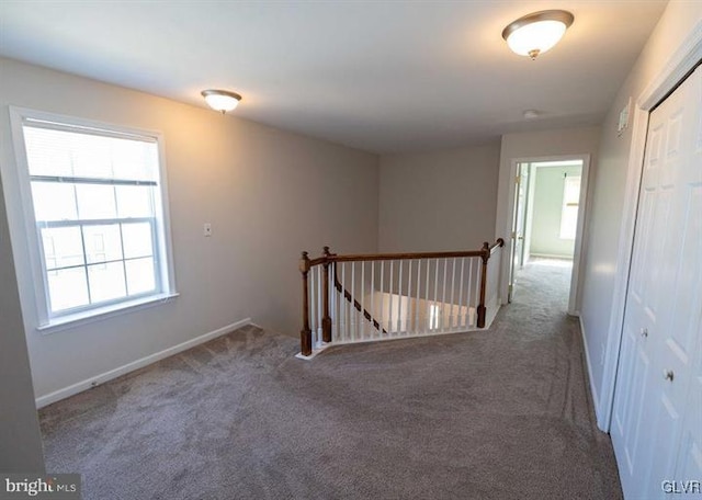 hallway with baseboards, an upstairs landing, and carpet