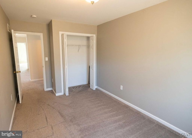 unfurnished bedroom with a closet, carpet floors, and baseboards