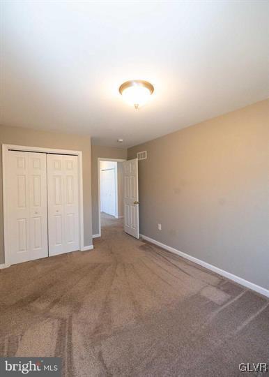 unfurnished bedroom with carpet, a closet, and baseboards