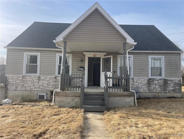 view of front of home with covered porch, stone siding, and a shingled roof