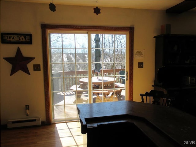 dining area with a baseboard heating unit and wood finished floors