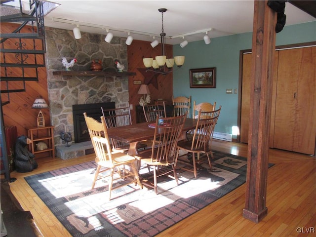 dining space featuring rail lighting, a fireplace, wood-type flooring, and a baseboard radiator