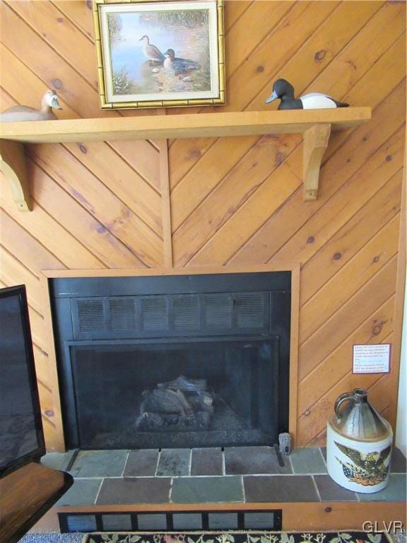 interior details with wood walls and a tile fireplace