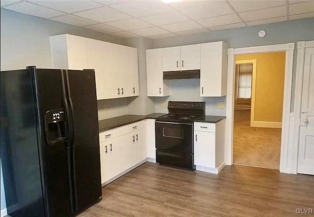 515 N Railroad St, Tamaqua Borough, PA 18252 - kitchen with dark countertops, black appliances, dark wood-type flooring, under cabinet range hood, and white cabinetry