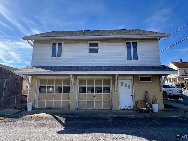 view of front of property with a garage and roof with shingles