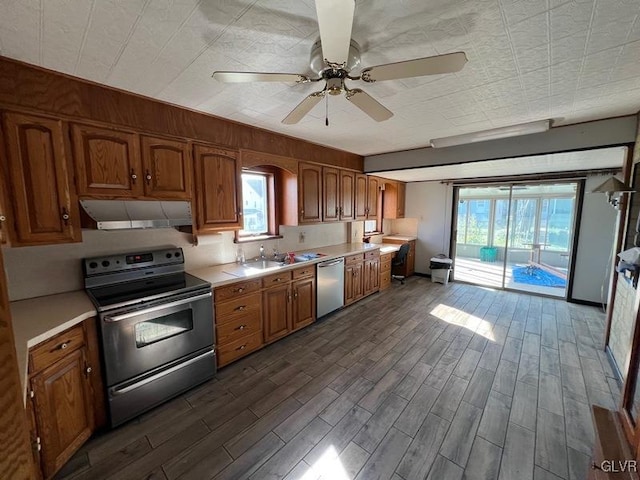 kitchen with range hood, a ceiling fan, brown cabinetry, light countertops, and appliances with stainless steel finishes