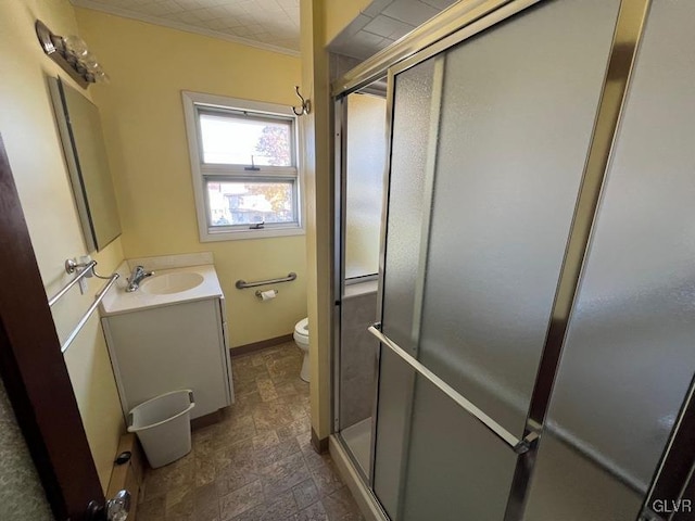 bathroom with vanity, a stall shower, stone finish floor, crown molding, and toilet