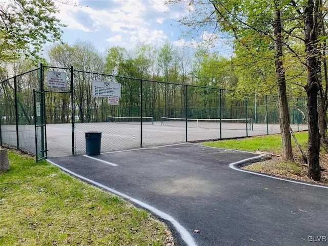 view of basketball court featuring a tennis court and fence