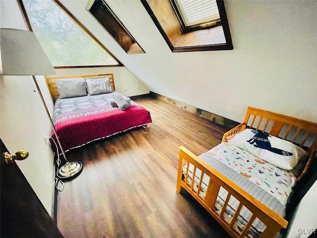 bedroom with a skylight and wood finished floors