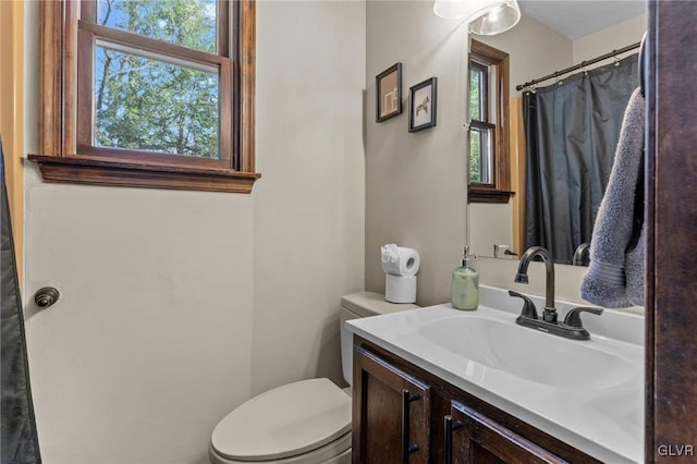 full bath featuring toilet, plenty of natural light, and vanity