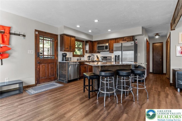 156 Poplar Pl, Tunkhannock Township, PA 18610 - kitchen with a breakfast bar area, light stone countertops, dark wood finished floors, stainless steel appliances, and recessed lighting