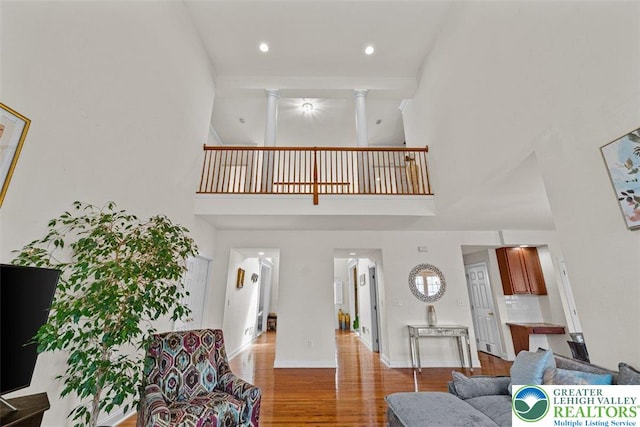 255 Rising Meadow Way E, Stroudsburg, PA 18302 - living area featuring a towering ceiling, wood finished floors, ornate columns, and recessed lighting