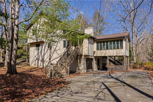 367 Saunders Dr, Lehman Twp, PA 18324 - back of property with stairs, driveway, roof with shingles, a chimney, and a sunroom