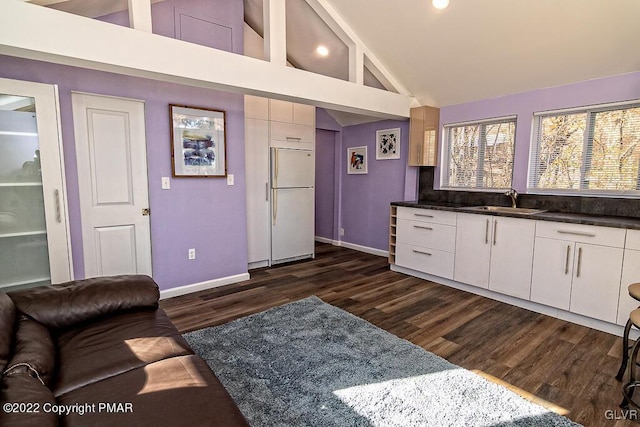 kitchen featuring dark wood-style flooring, baseboards, dark countertops, built in fridge, and white cabinets