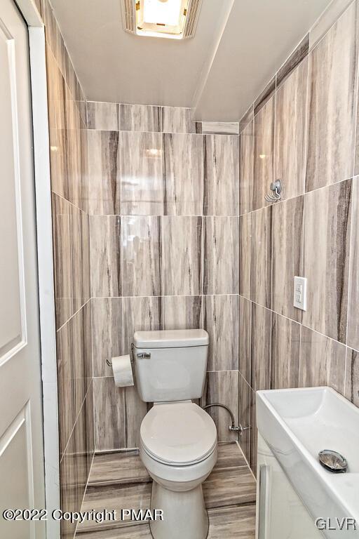 bathroom with toilet and tile walls