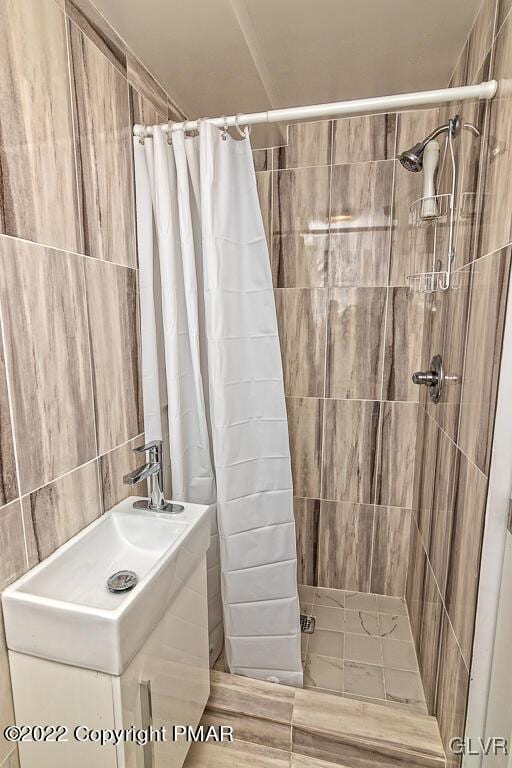 bathroom featuring tile walls, vanity, and tiled shower