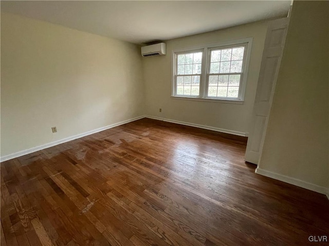 spare room featuring dark wood-style flooring, baseboards, and an AC wall unit