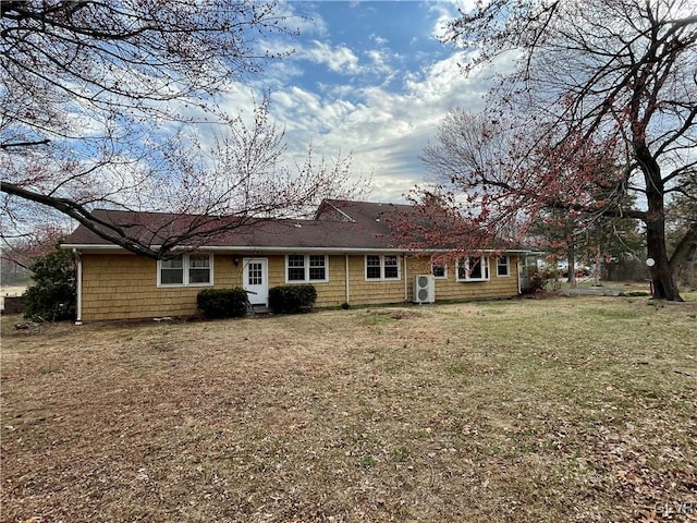 rear view of house with a yard and roof with shingles