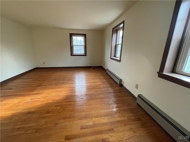 empty room featuring baseboards, light wood-style floors, and baseboard heating