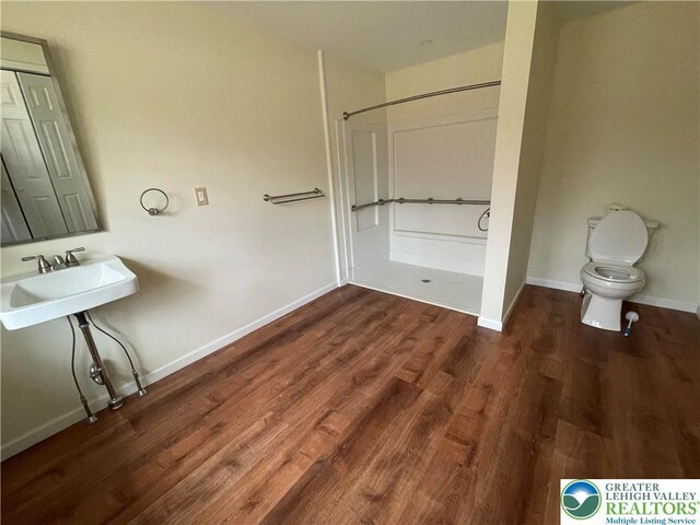 full bathroom featuring toilet, wood finished floors, a sink, baseboards, and walk in shower