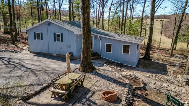 rear view of property featuring an outdoor fire pit, crawl space, a shingled roof, and a patio area