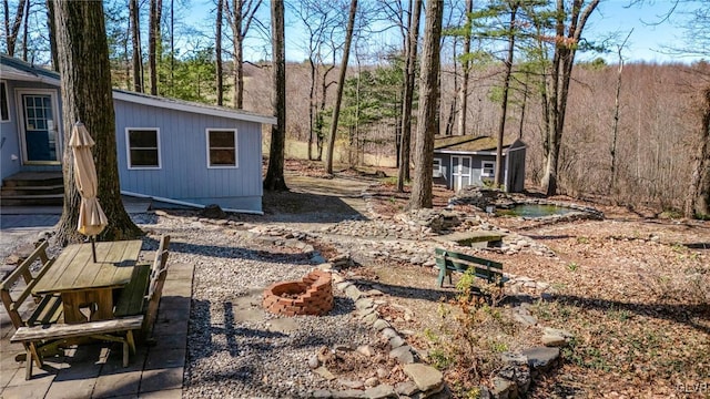view of yard featuring a patio, a fire pit, an outdoor structure, and entry steps