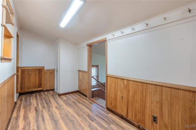 spare room featuring a wainscoted wall, lofted ceiling, and light wood-style flooring