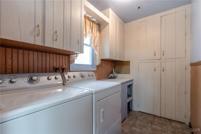 laundry room featuring washing machine and dryer, wood walls, and cabinet space