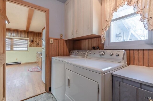 clothes washing area with cabinet space, wooden walls, washer and clothes dryer, and a baseboard radiator