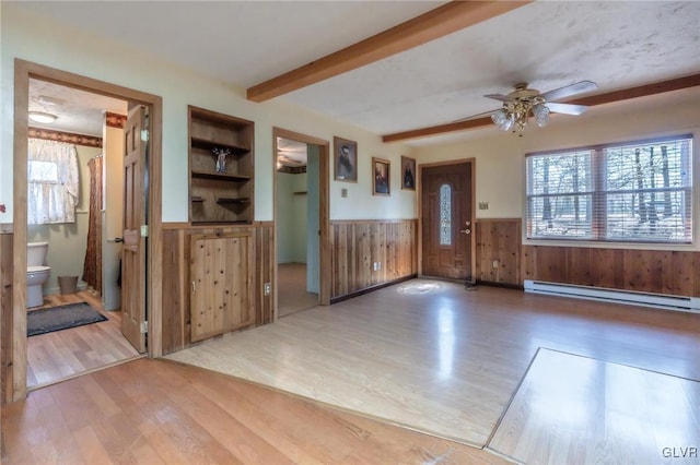 foyer with wainscoting, beam ceiling, a baseboard heating unit, and a healthy amount of sunlight