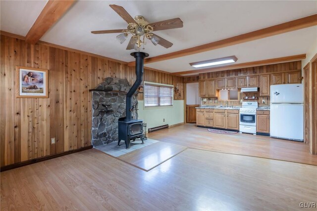 kitchen featuring stove, a wood stove, beam ceiling, light wood-style floors, and freestanding refrigerator