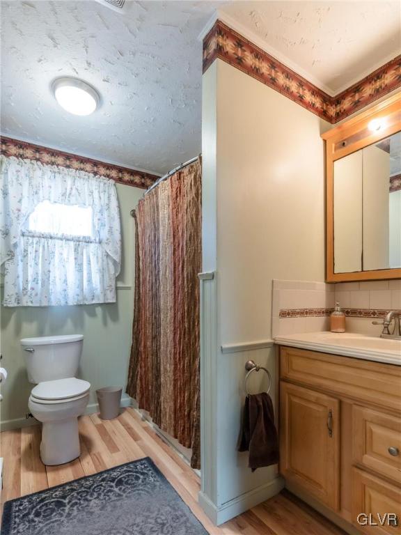 bathroom featuring a shower with shower curtain, wood finished floors, toilet, and a textured ceiling